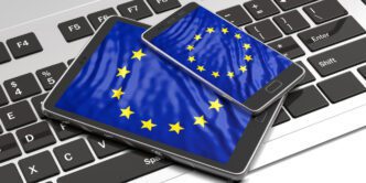 A tablet and a smartphone with the EU flag displayed on their screens, resting on a laptop keyboard