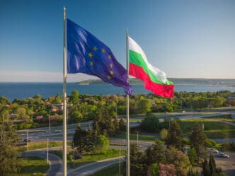 EU and Bulgarian flags flying over Varna, Bulgaria, with the sea and city in the background