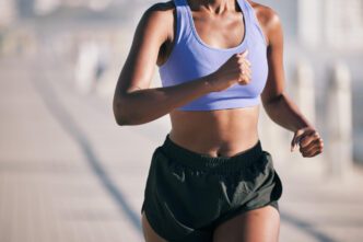 A female runner in athletic shorts and a sports bra, captured in motion during a run