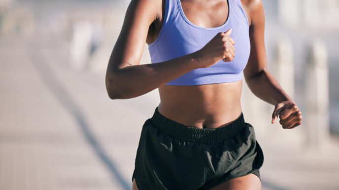 A female runner in athletic shorts and a sports bra, captured in motion during a run