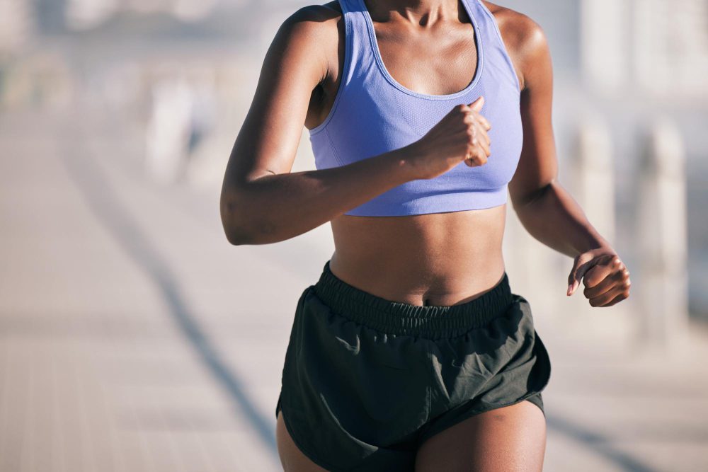 A female runner in athletic shorts and a sports bra, captured in motion during a run