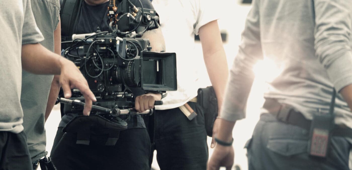A film crew operates a professional video camera on a set