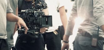 A film crew operates a professional video camera on a set