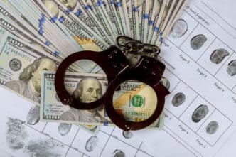 Handcuffs, US dollars, and fingerprint cards symbolize financial crime