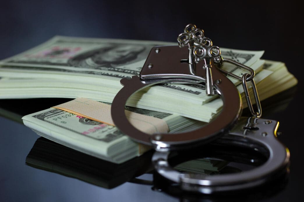 Handcuffs with keys on a stack of US dollar bills