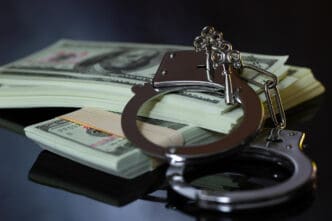 Handcuffs with keys on a stack of US dollar bills