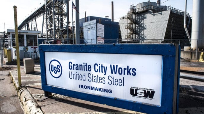 A sign for USS Granite City Works, United States Steel, with the ironmaking facility visible in the background