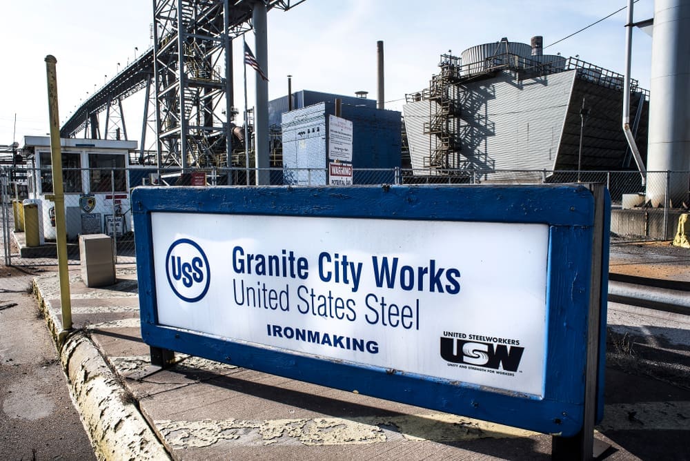A sign for USS Granite City Works, United States Steel, with the ironmaking facility visible in the background