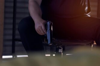 A person is sitting down and holding a handgun, with a focus on the weapon