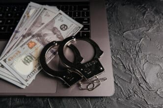 Handcuffs and money lie on a laptop keyboard