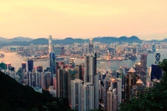 A panoramic view of the Hong Kong skyline at dusk with mountains in the background