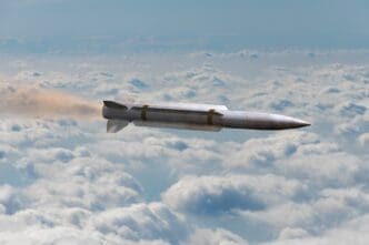 A missile flies through clouds, leaving a trail of smoke