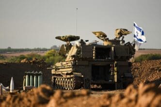 An IDF M109 artillery cannon is positioned on a dirt mound with an Israeli flag, prepared to fire