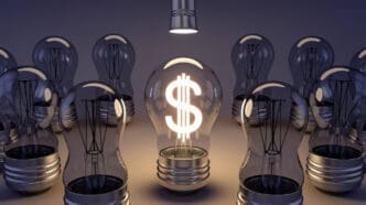 A lit lightbulb with a dollar sign inside is surrounded by unlit lightbulbs