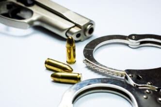 Handcuffs and bullets near a handgun on a white surface