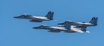 Three Israeli F-15 fighter jets fly in a tight formation against a clear blue sky