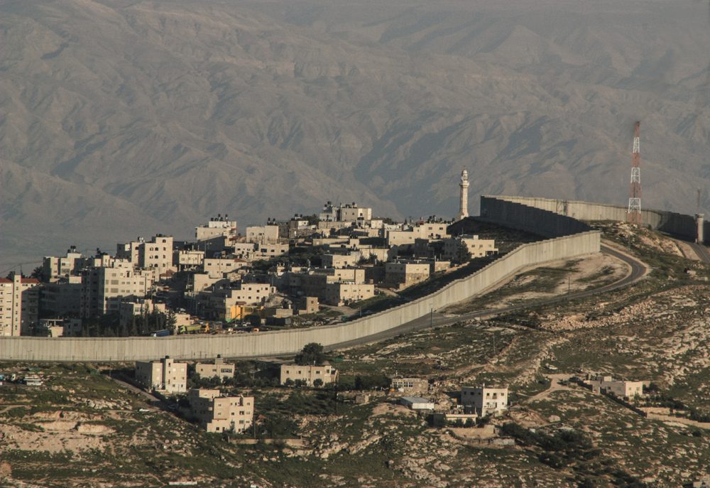 The Israeli West Bank barrier, a large concrete wall, separates a Palestinian town from the surrounding land