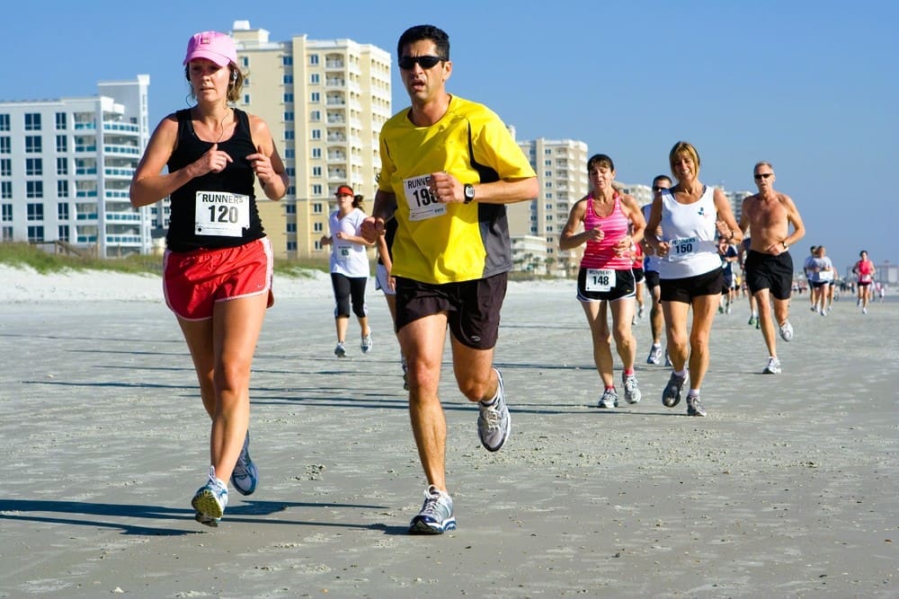 A group of runners competes in the Jacksonville Beach 10-mile beach run on a sunny day in Florida