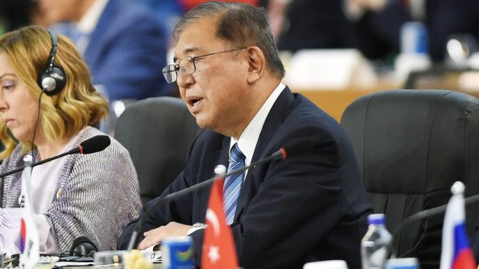 Shigeru Ishiba, Prime Minister of Japan, speaking at a meeting in front of a microphone