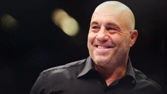 Close-up of Joe Rogan smiling against a blurred dark background