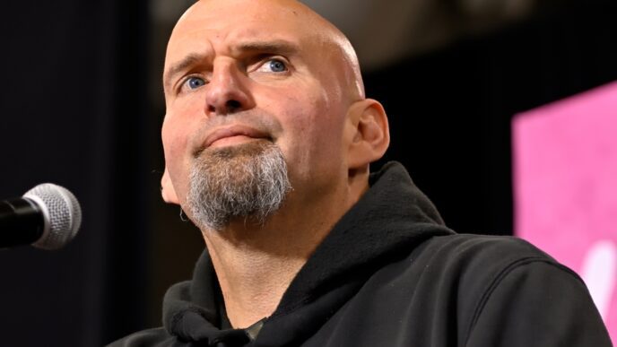 John Fetterman, a bald man with a goatee, looks upward while speaking into a microphone