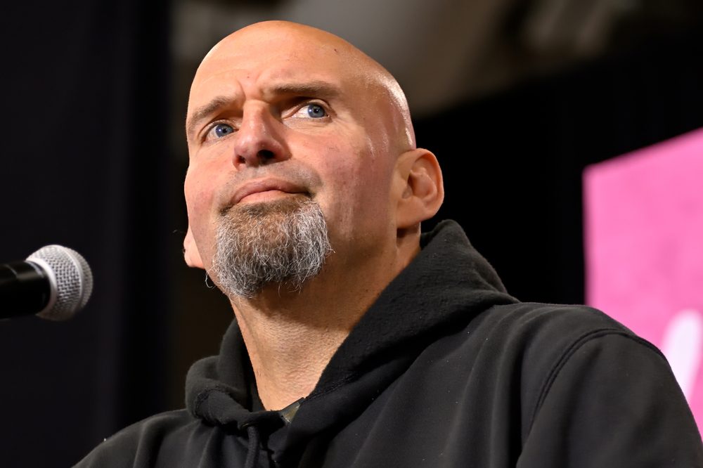 John Fetterman, a bald man with a goatee, looks upward while speaking into a microphone