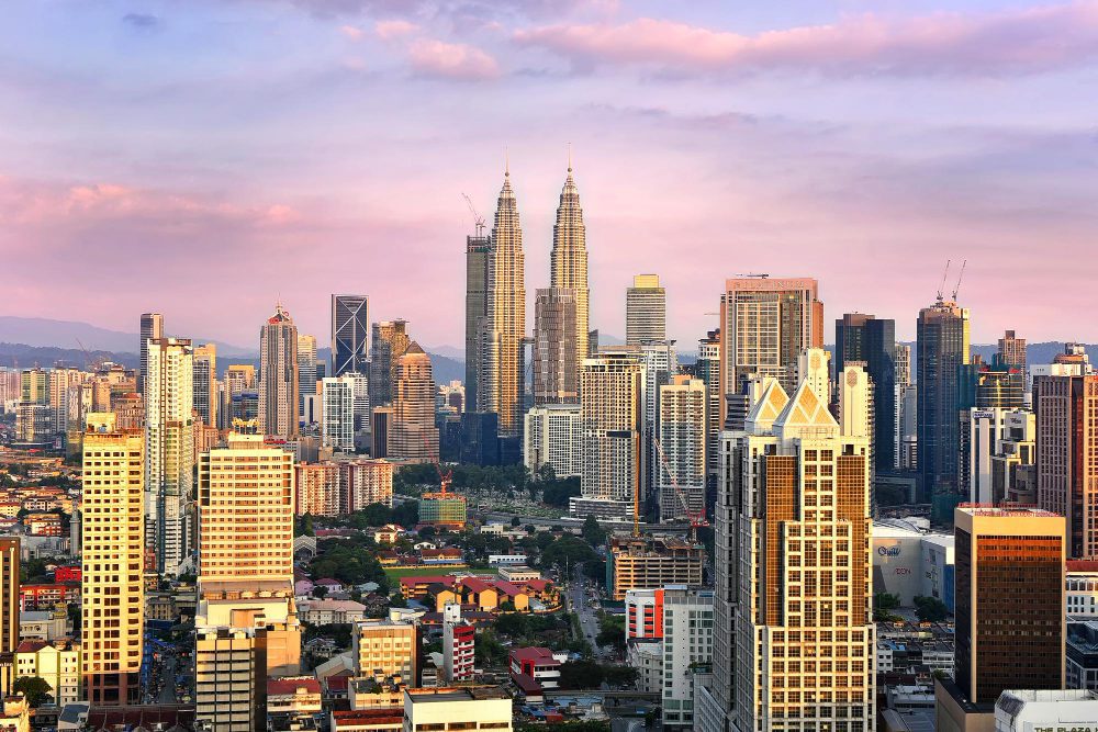 The panoramic skyline of Kuala Lumpur with the iconic Petronas Towers at sunset
