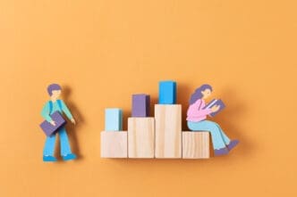 Paper cutouts of two people and wooden blocks form a conceptual image about education and the labor market