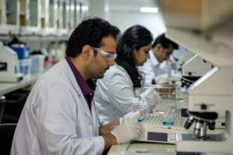 Scientists in a lab examine test tubes and equipment