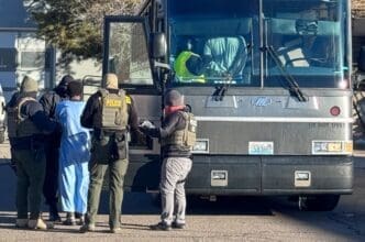 Armed agents from ICE, DEA, and FBI conduct a raid, detaining a person near a large bus in Denver, Colorado