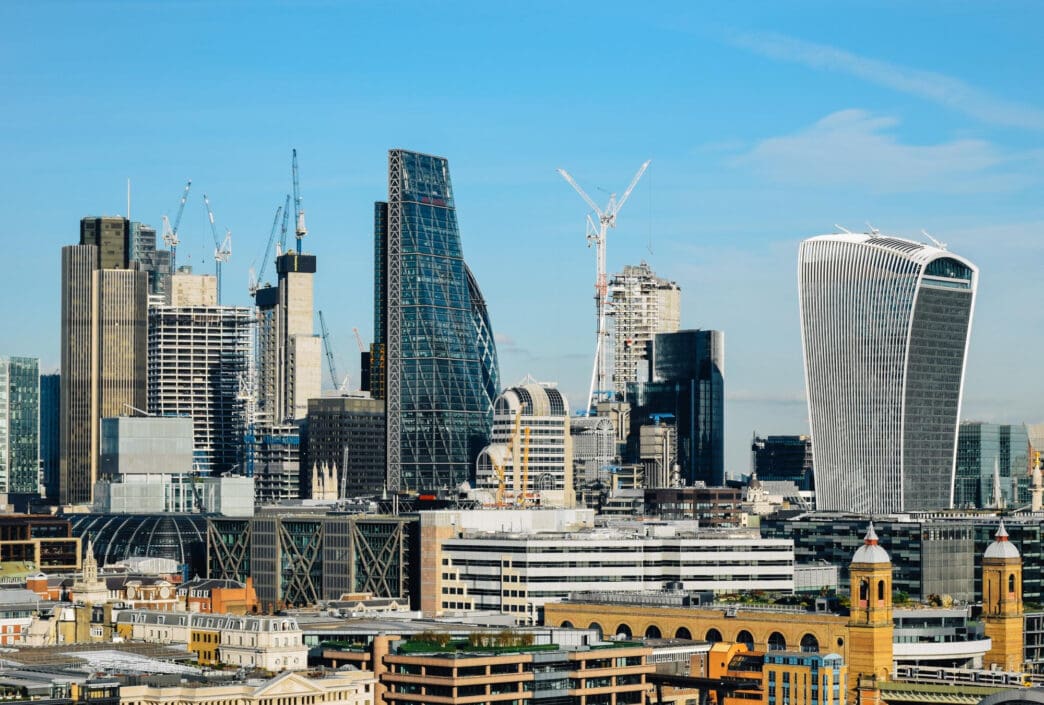 The skyline of London's financial district with multiple modern skyscrapers and construction cranes