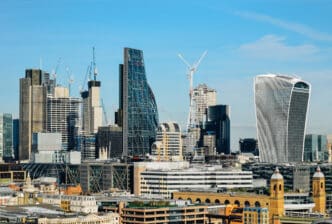 The skyline of London's financial district with multiple modern skyscrapers and construction cranes