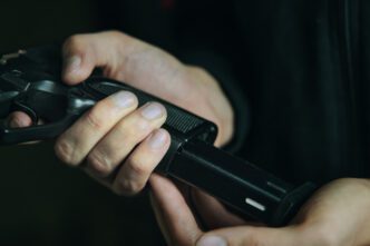 A person reloading a handgun by inserting a magazine of ammunition into the grip