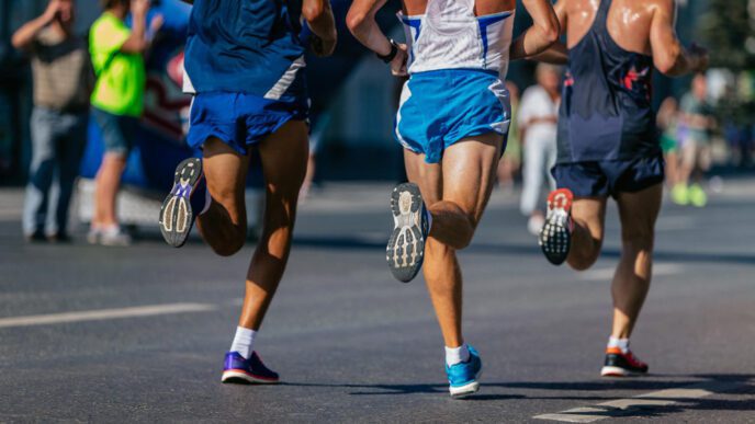 Three male runners are shown from behind, jogging on a street during a marathon