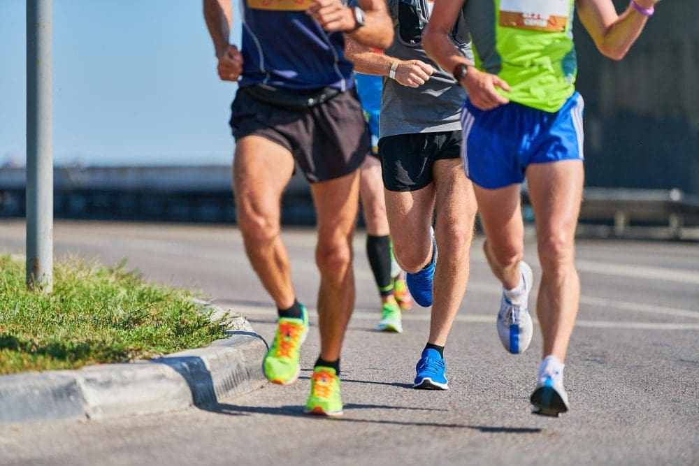 Three male runners in shorts and running shoes competing in a marathon
