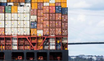 The side of a large container ship is filled with stacked cargo containers in a variety of colors