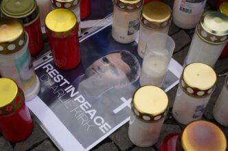 A makeshift memorial with candles and a printed photo of Charlie Kirk on a cobblestone street