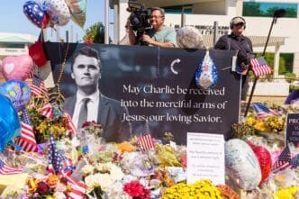 A memorial display with a portrait of Charlie Kirk and flowers