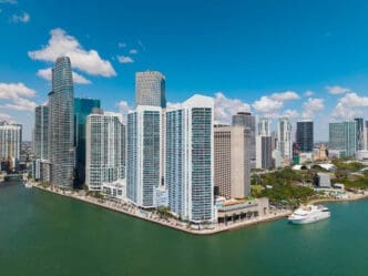 An aerial view of Miami's downtown skyline and waterfront with a modern yacht