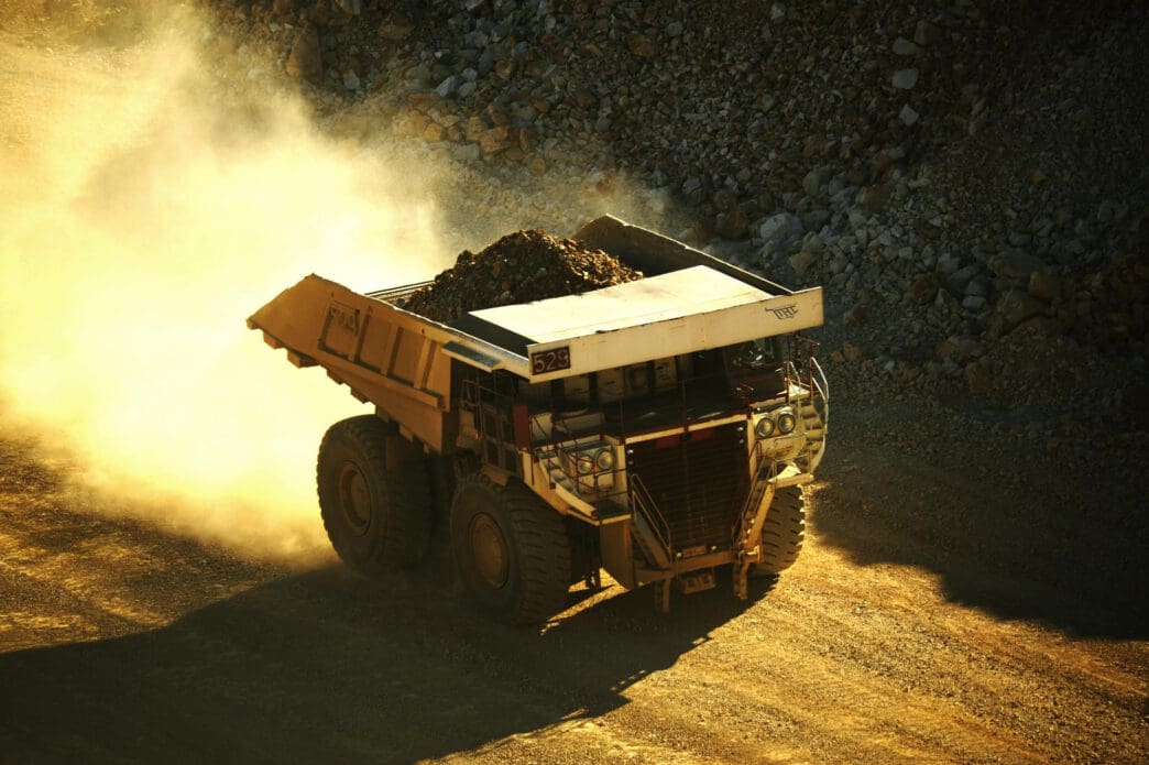 Large mining truck driving on a dusty road, carrying rare earth minerals