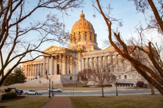 The Missouri State Capitol building is shown with a grand dome on a late afternoon