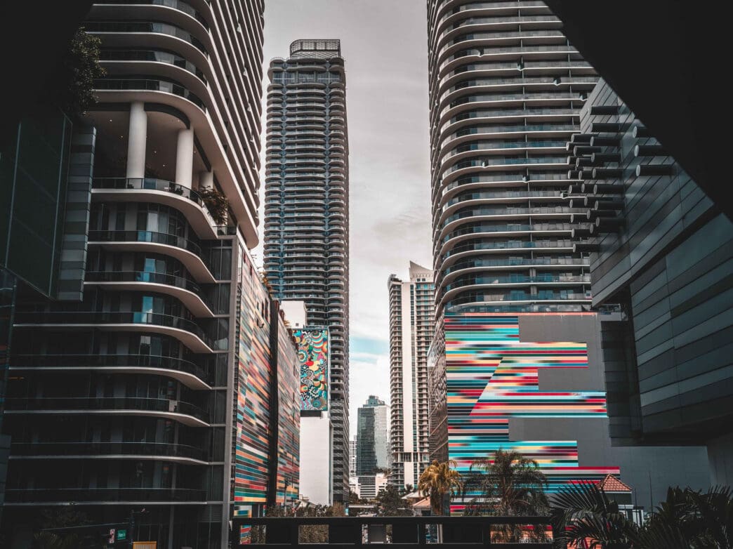 Tall modern buildings with colorful murals line a street in Miami