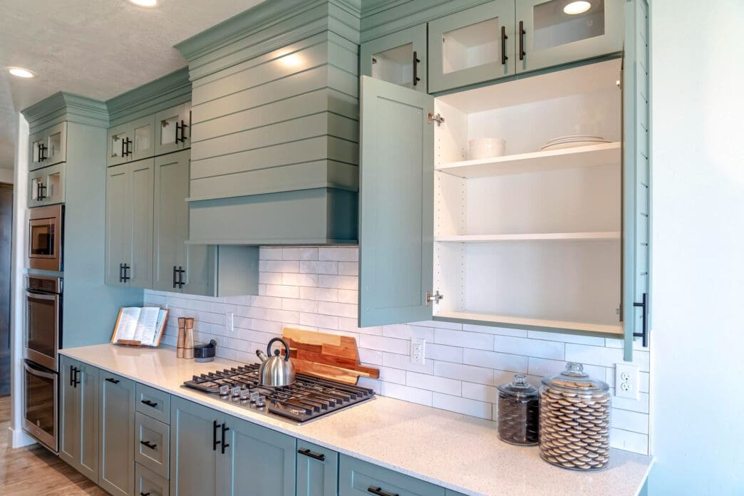 A modern kitchen features light blue cabinets, a gas stove, and white subway tile backsplash.