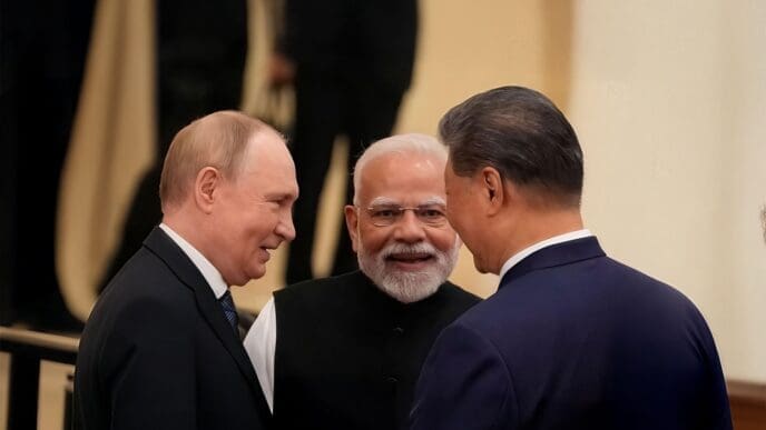 Three world leaders, including Indian PM Narendra Modi, Russian President Vladimir Putin, and Chinese President Xi Jinping, talk and smile together in a formal indoor setting