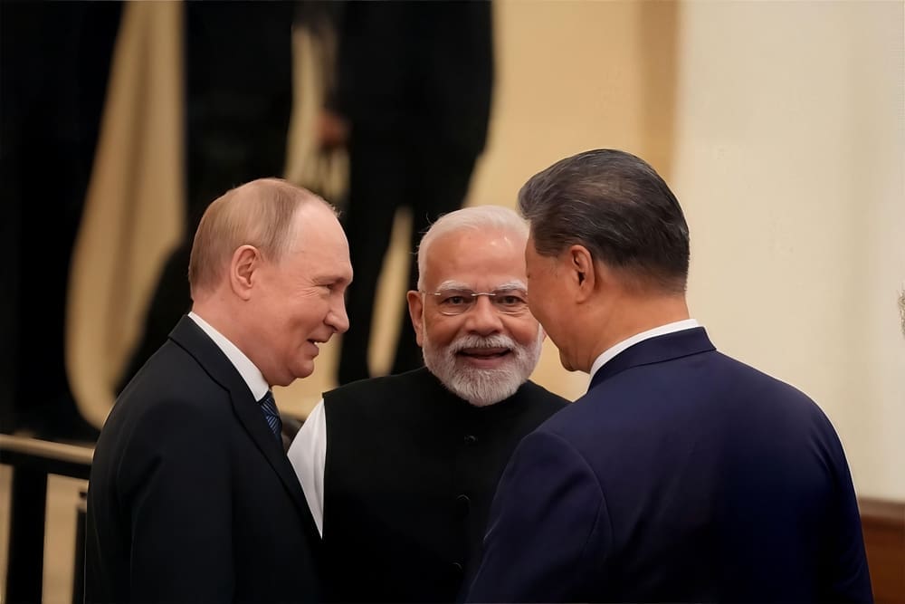 Three world leaders, including Indian PM Narendra Modi, Russian President Vladimir Putin, and Chinese President Xi Jinping, talk and smile together in a formal indoor setting
