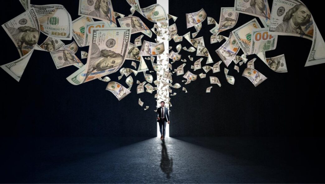 A businessman walks through a glowing doorway with one hundred dollar bills flying around him