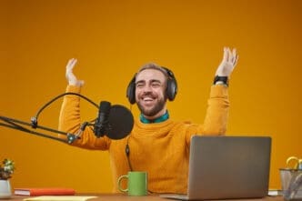 Enthusiastic podcaster with headphones and raised arms in front of a microphone