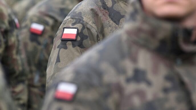 A close-up of a Polish flag patch on the sleeve of a soldier's camouflage uniform