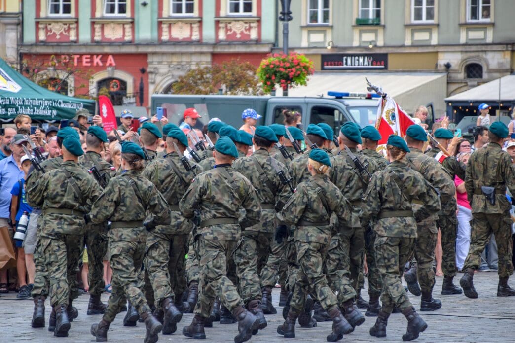 Polish soldiers in camouflage march in formation with bayonets fixed