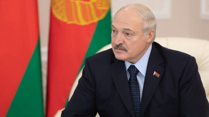 Alexander Lukashenko sits at a table with the flag of Belarus visible behind him